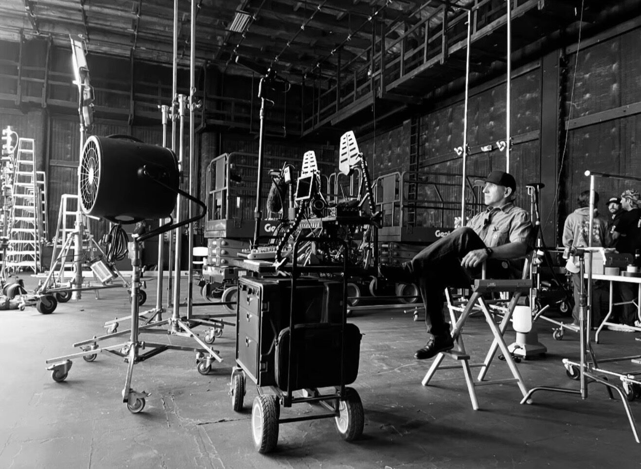 Luis Martinez sitting in a director's chair on a soundstage next to his rolling prop cart, surrounded by C-stands and lifts